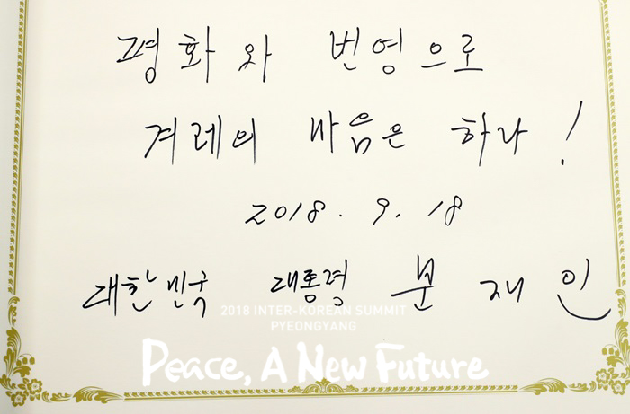 President Moon Jae-in writes, 'Peace and prosperity, the one spirit of the people!' in the guest log at the Workers' Party of Korea offices in Pyeongyang on Sept. 18. (Pyeongyang Press Corps)